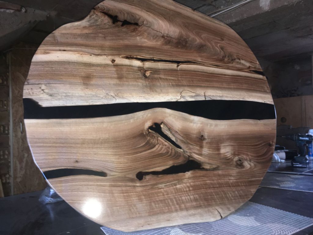 Round handmade epoxy resin table top with live edge wood and smoky resin river design from Eastern Europe.